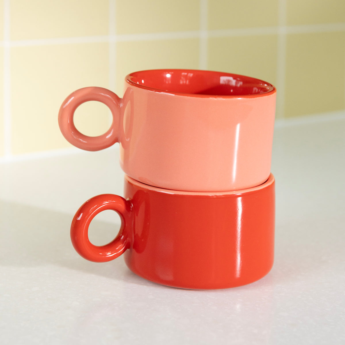 Pink and red Chiquito mugs stacked on a kitchen worktop