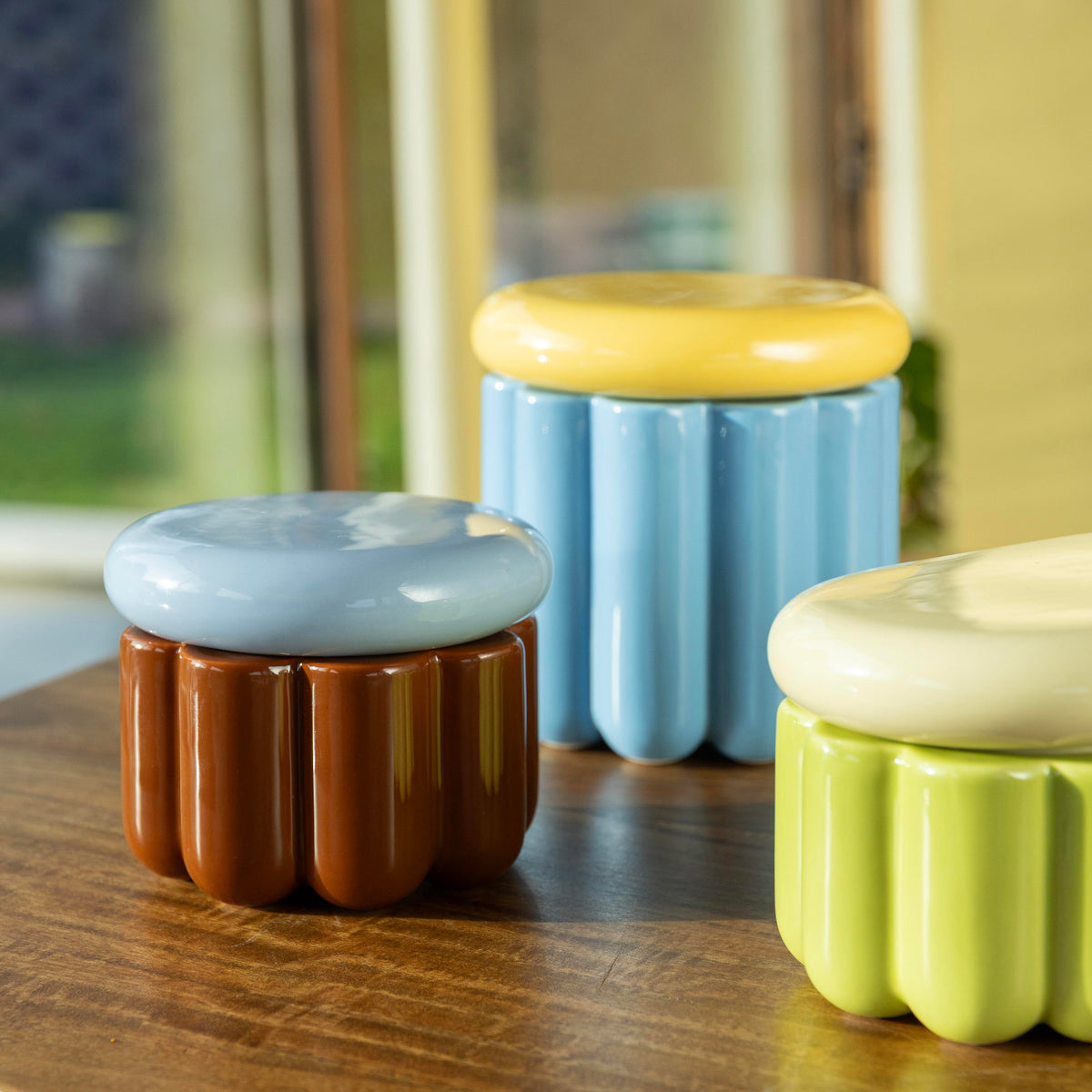 Charlo jars in blue, brown and green on a wooden table