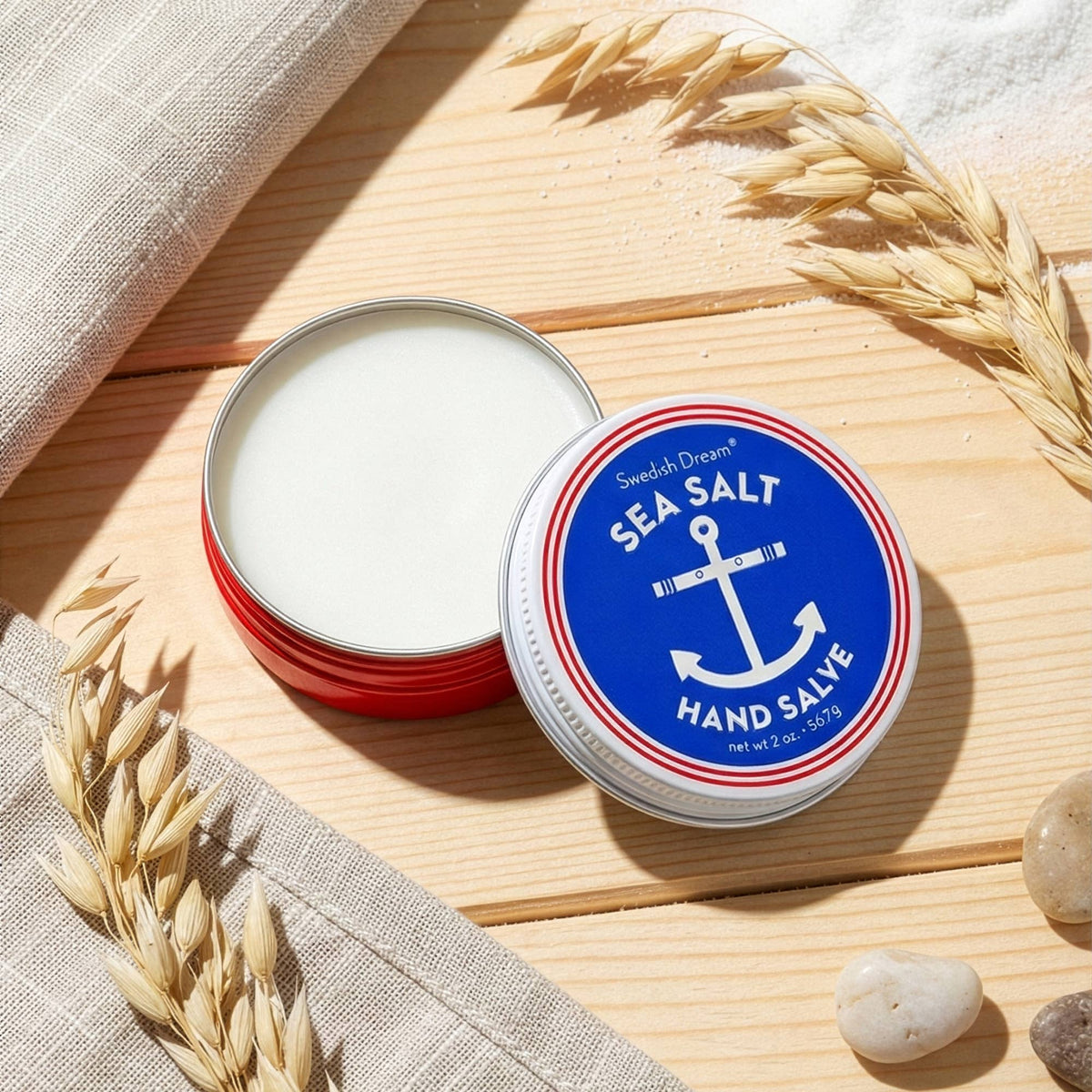 Open sea salt hand salve tin on a wooden board with wheat