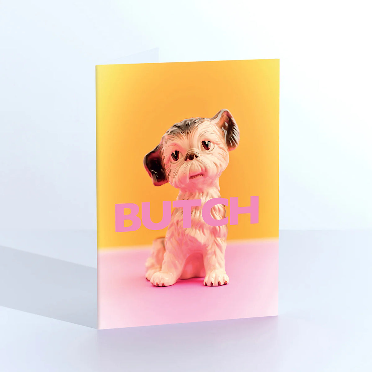 Ornament card: a vintage toy dog figurine with the word 'Butch' in pink on a yellow background