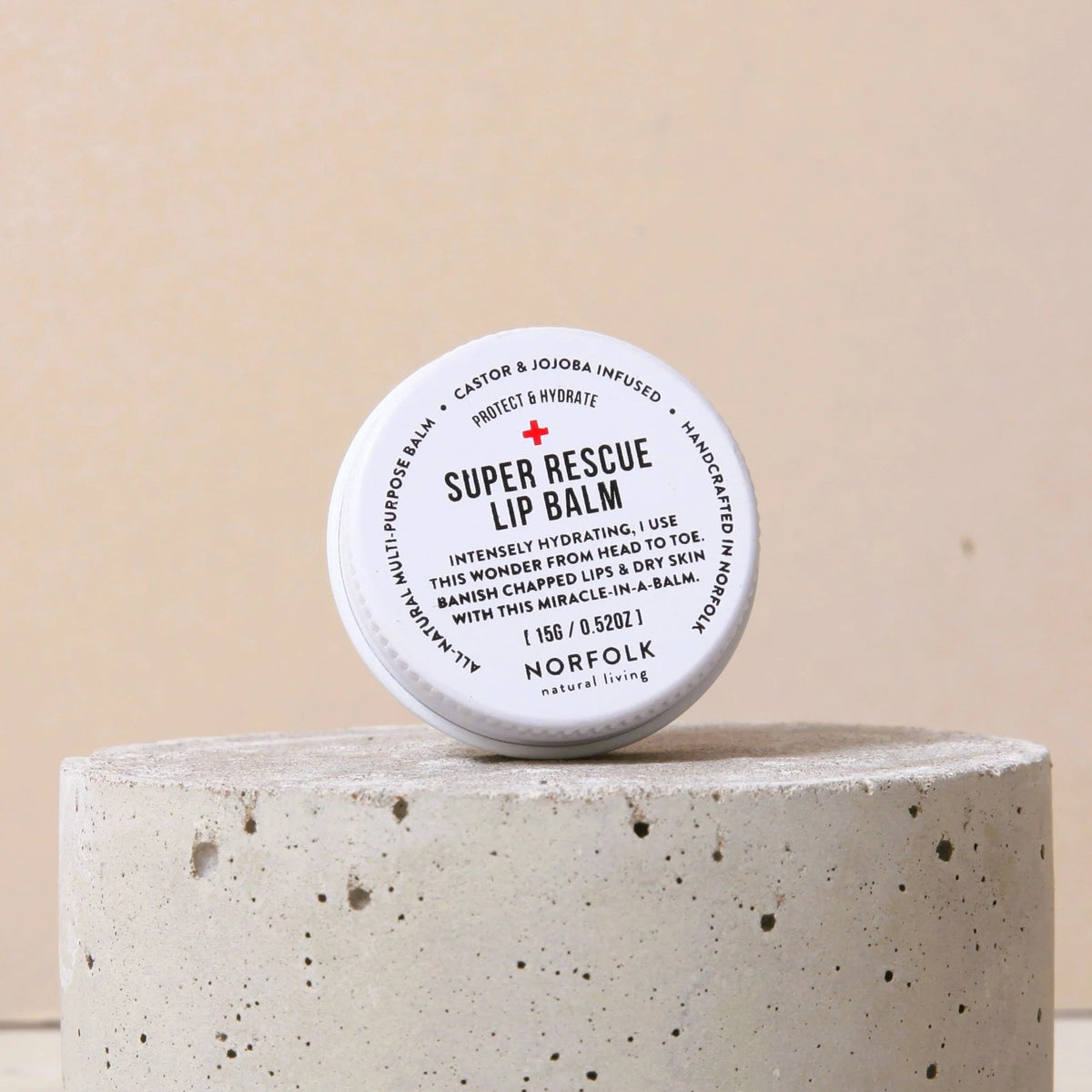 Norfolk Natural Living Super Rescue lip balm tin on a concrete block