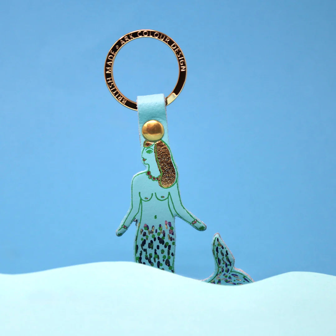 Ark blue mermaid leather key ring with a gold ring, against a blue background