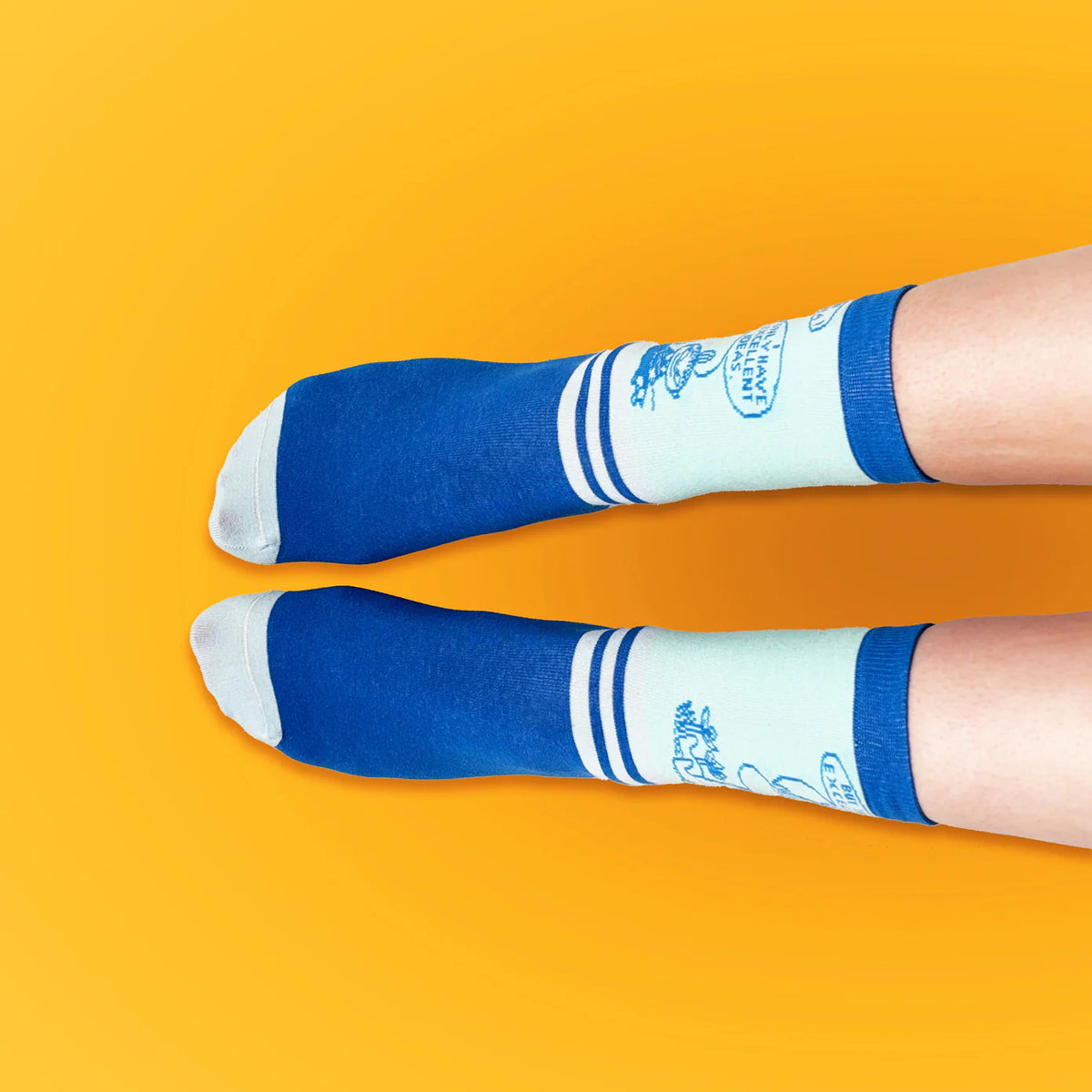 Feet wearing the Moomin Excellent Idea socks on yellow