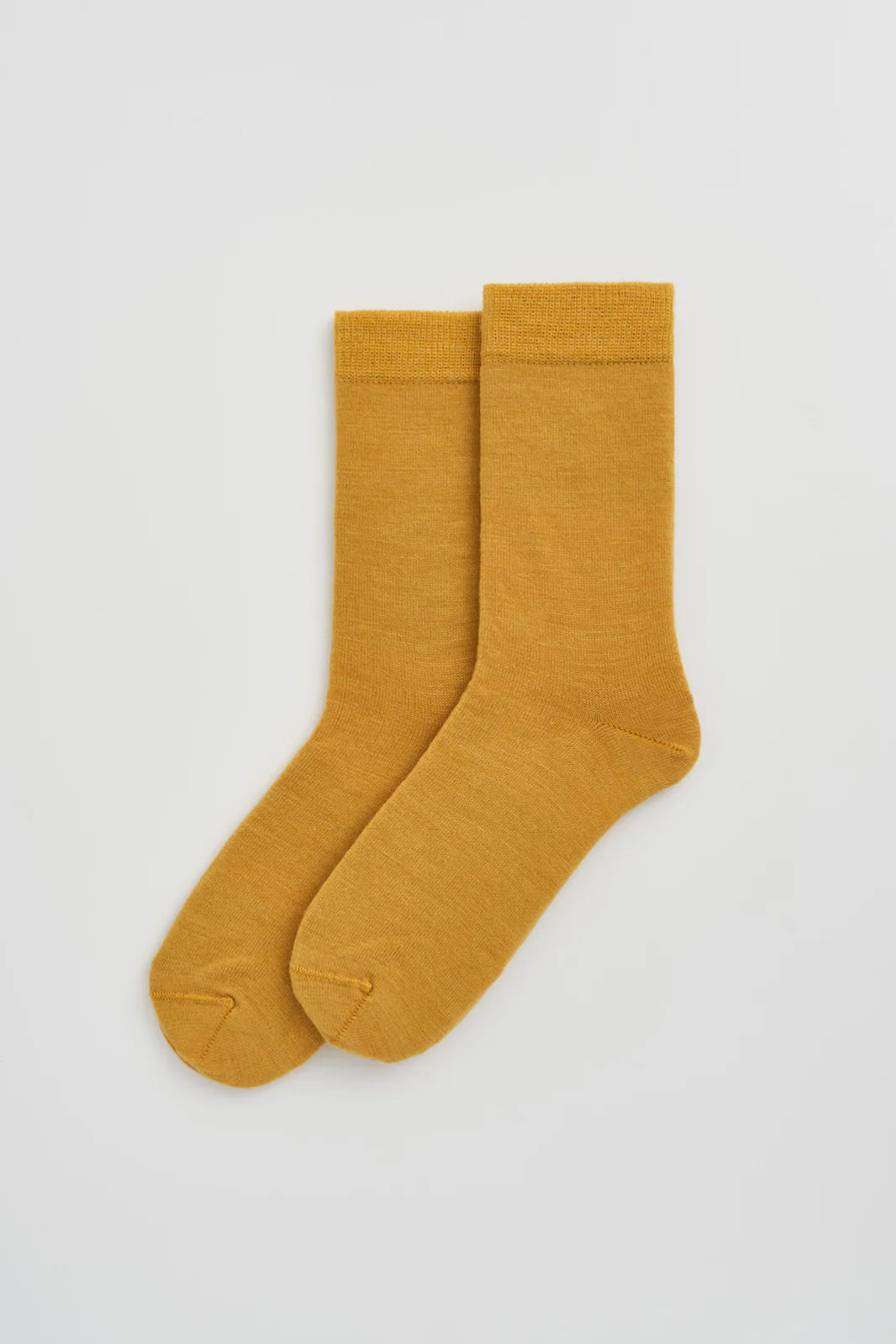 Pair of golden yellow calf-length merino socks laid flat