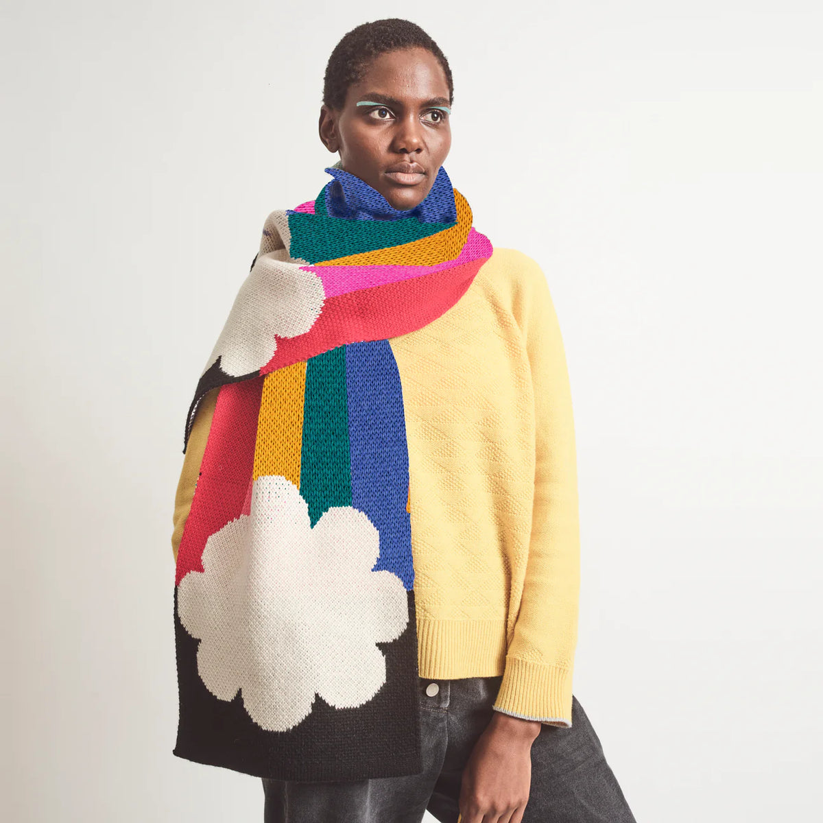 Model wearing the rainbow scarf wrapped around the neck with a yellow jumper