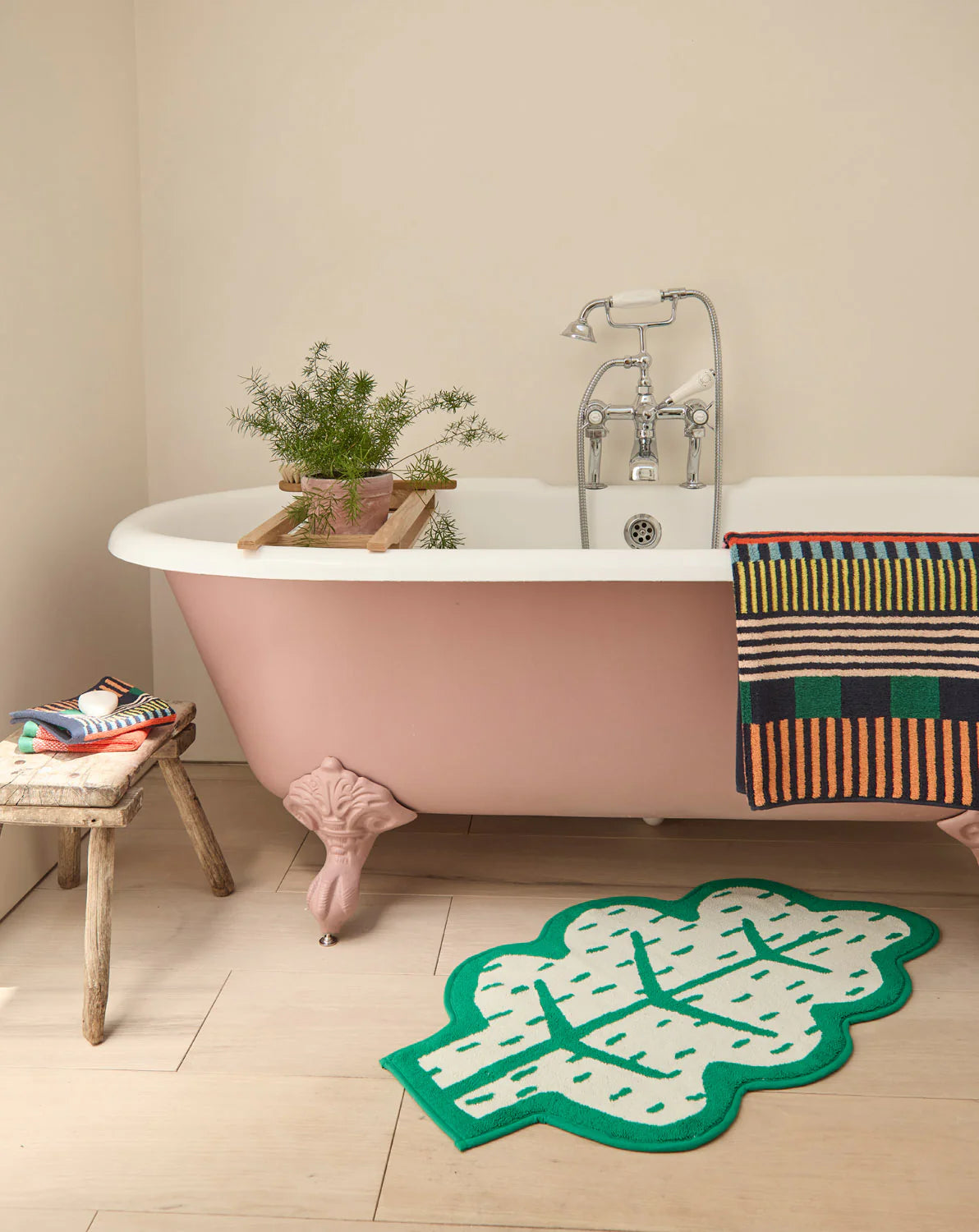 Leaf bath mat beside a pink clawfoot bath