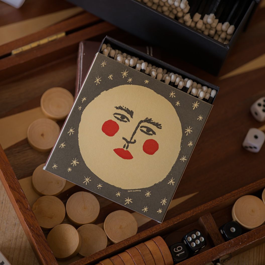 Moon matchbox resting on a wooden backgammon board