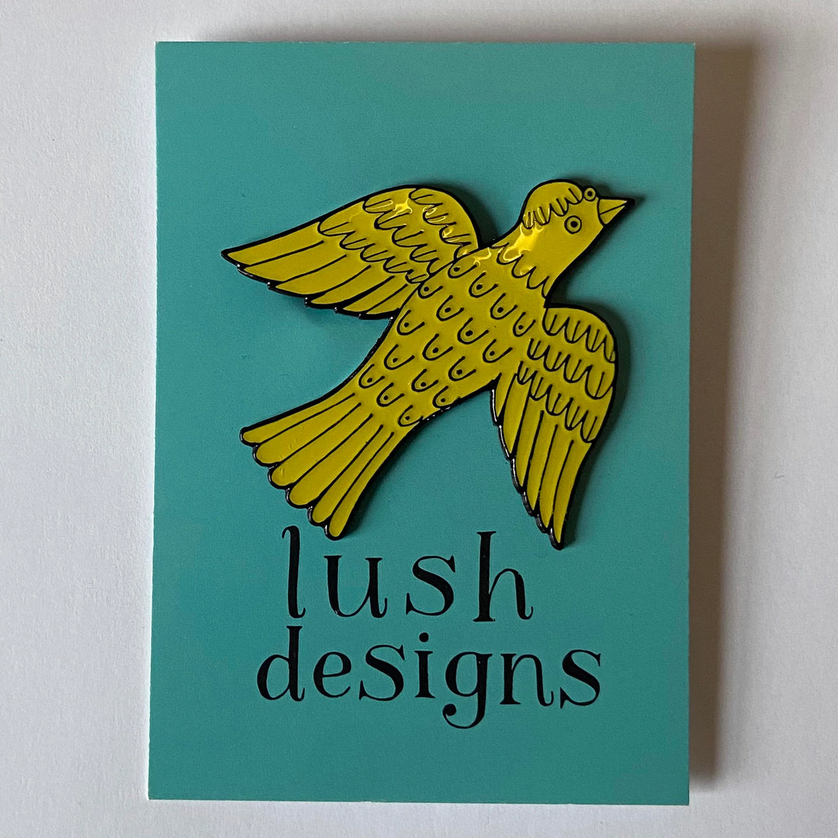 Yellow bird badge on its teal Lush Designs card
