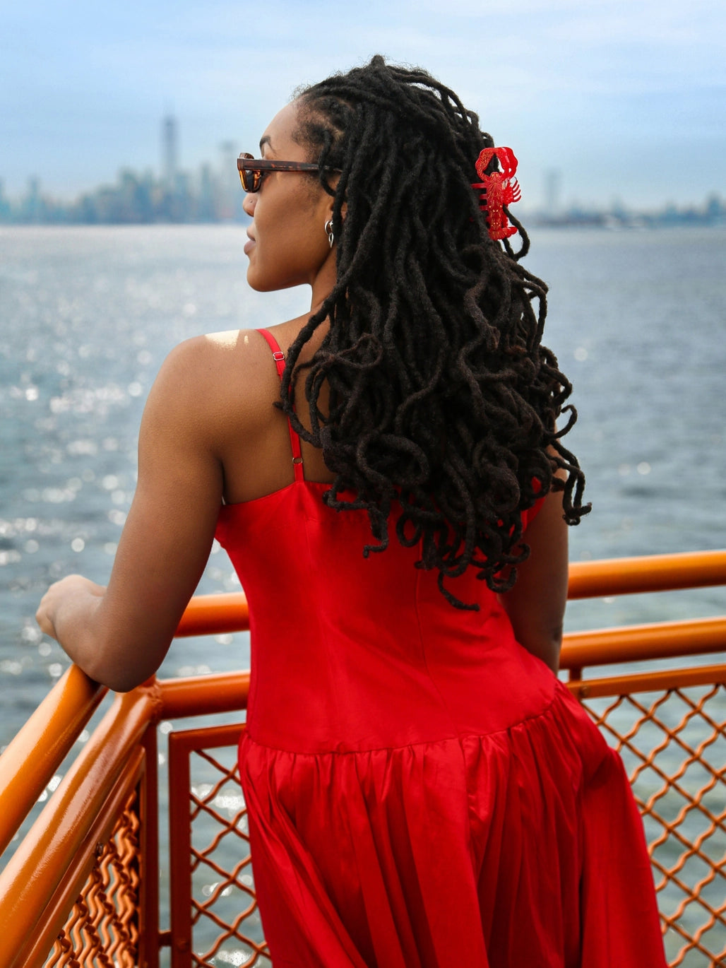 Red lobster claw clip in long dark curls by the water