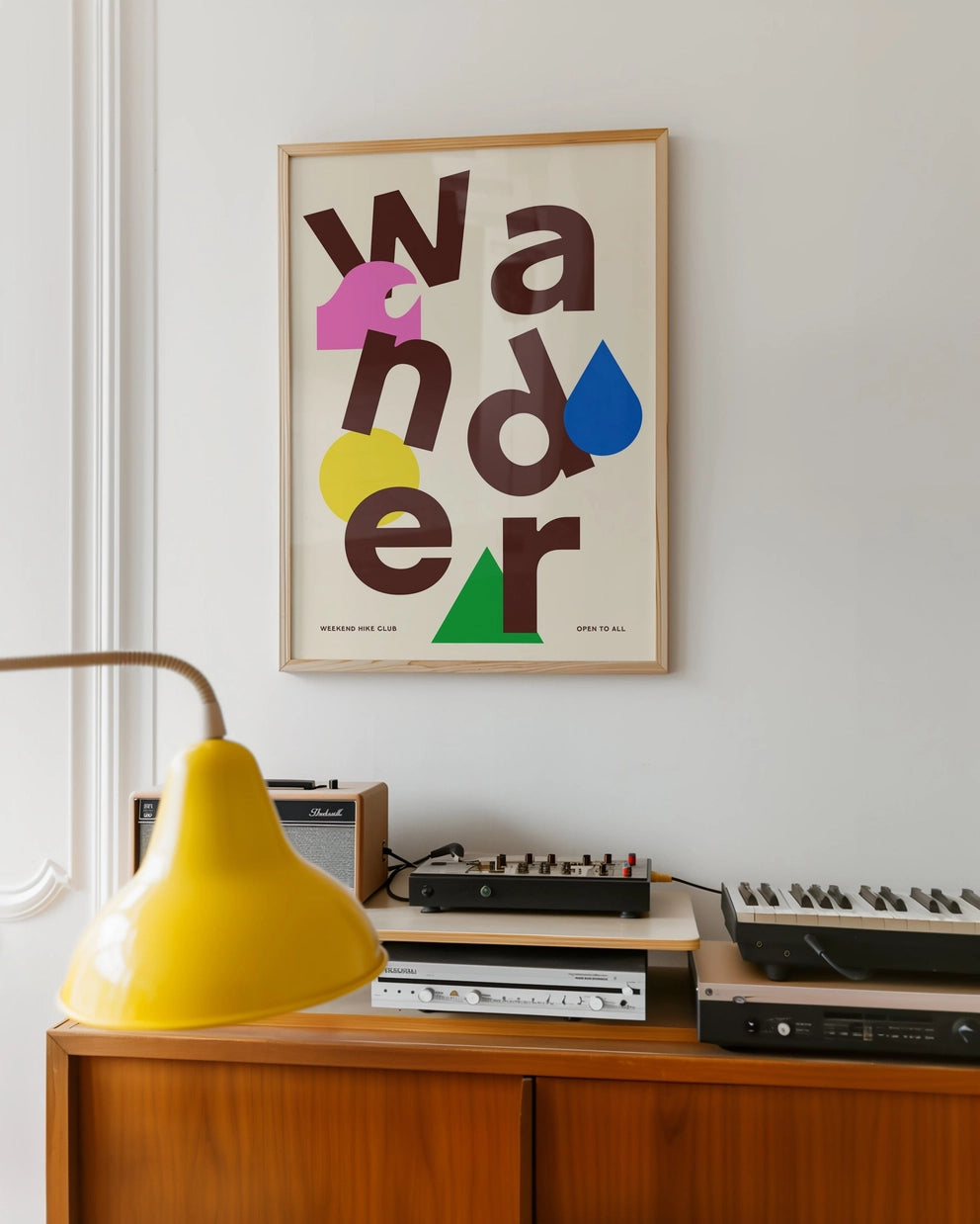 Wander print in a frame on a sideboard with a yellow lamp