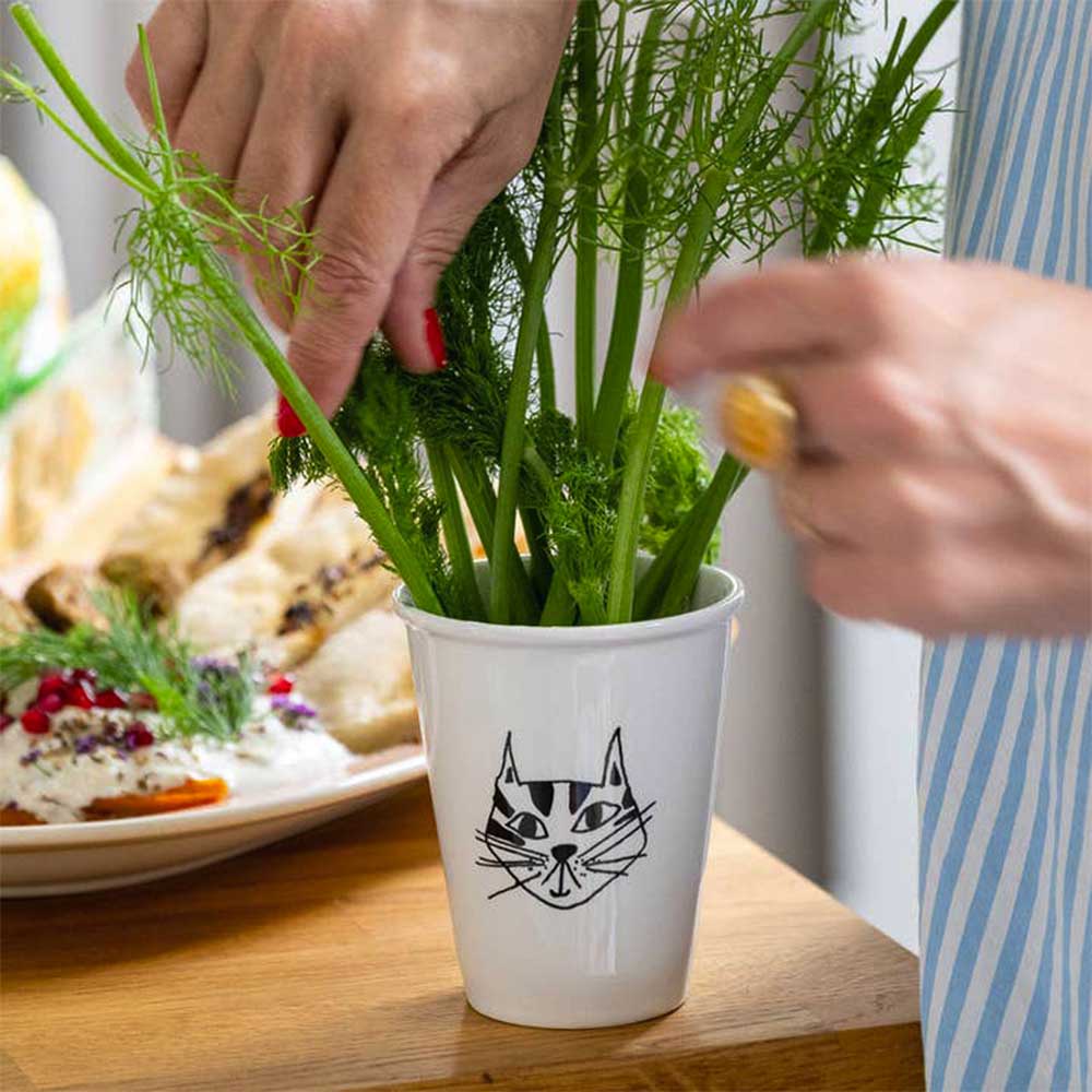 Kitty cup used as a vase for fennel fronds on a table