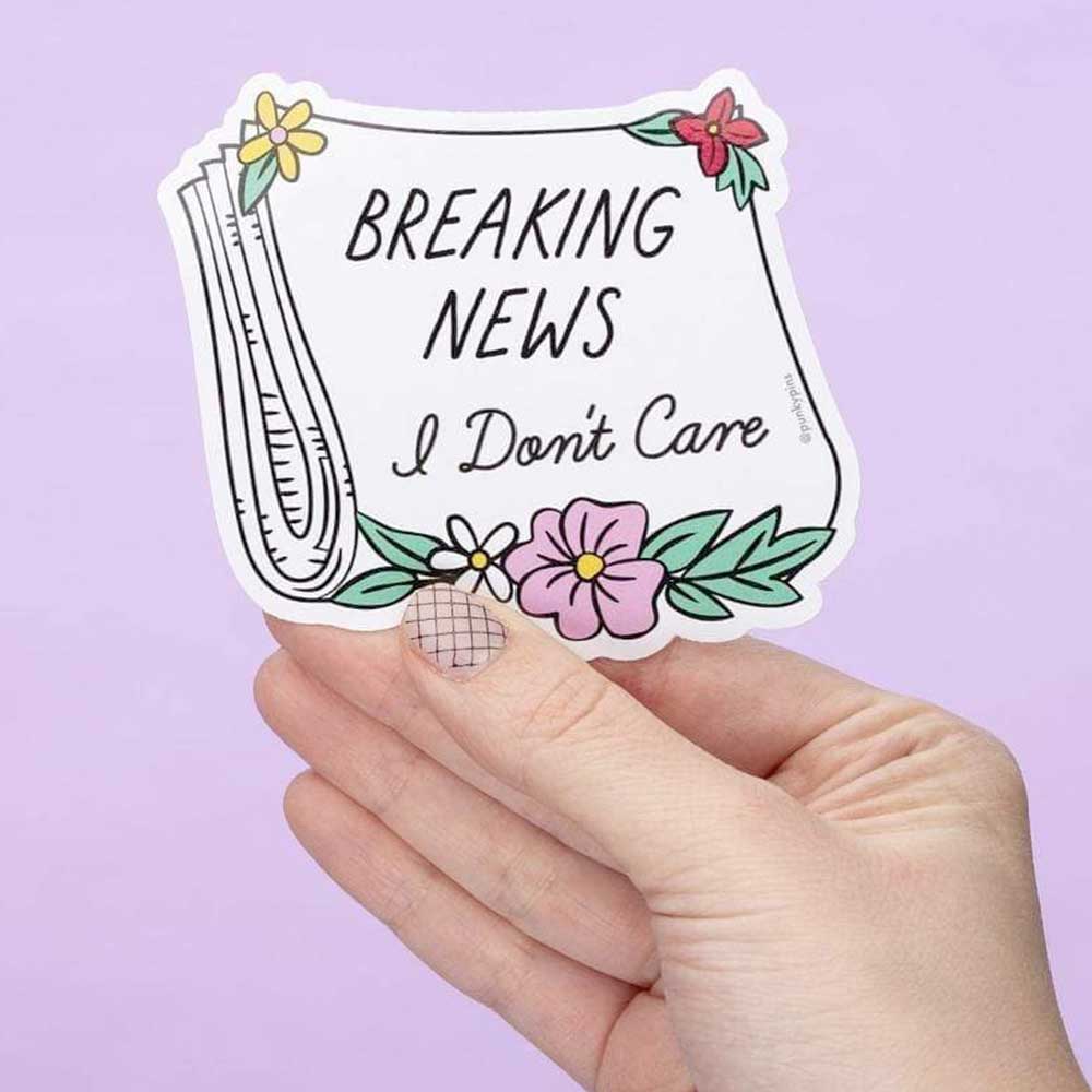 Hand holding a newspaper sticker with flowers: Breaking news, I don't care