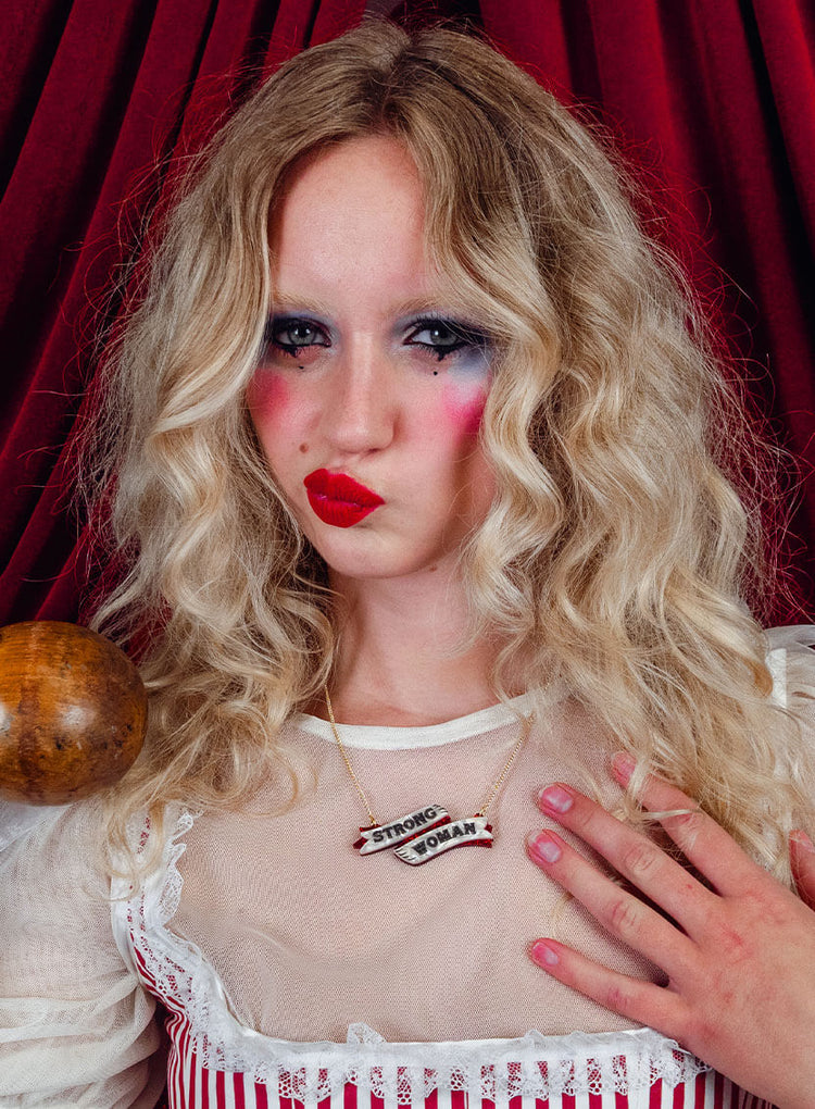 Woman with curly blonde hair and stage makeup wearing the Strong Woman necklace