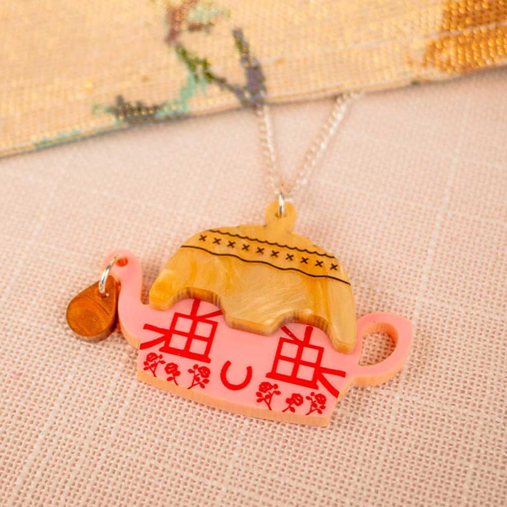 Cottage teapot pendant on embroidered fabric