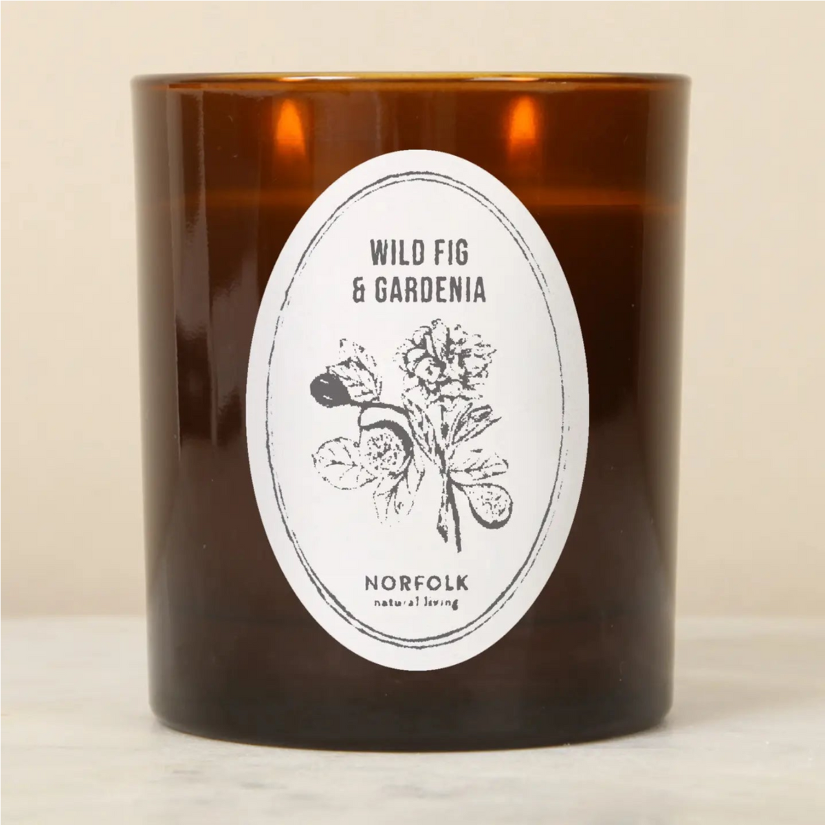 Norfolk Wild Fig & Gardenia candle in an amber glass jar with a white floral label