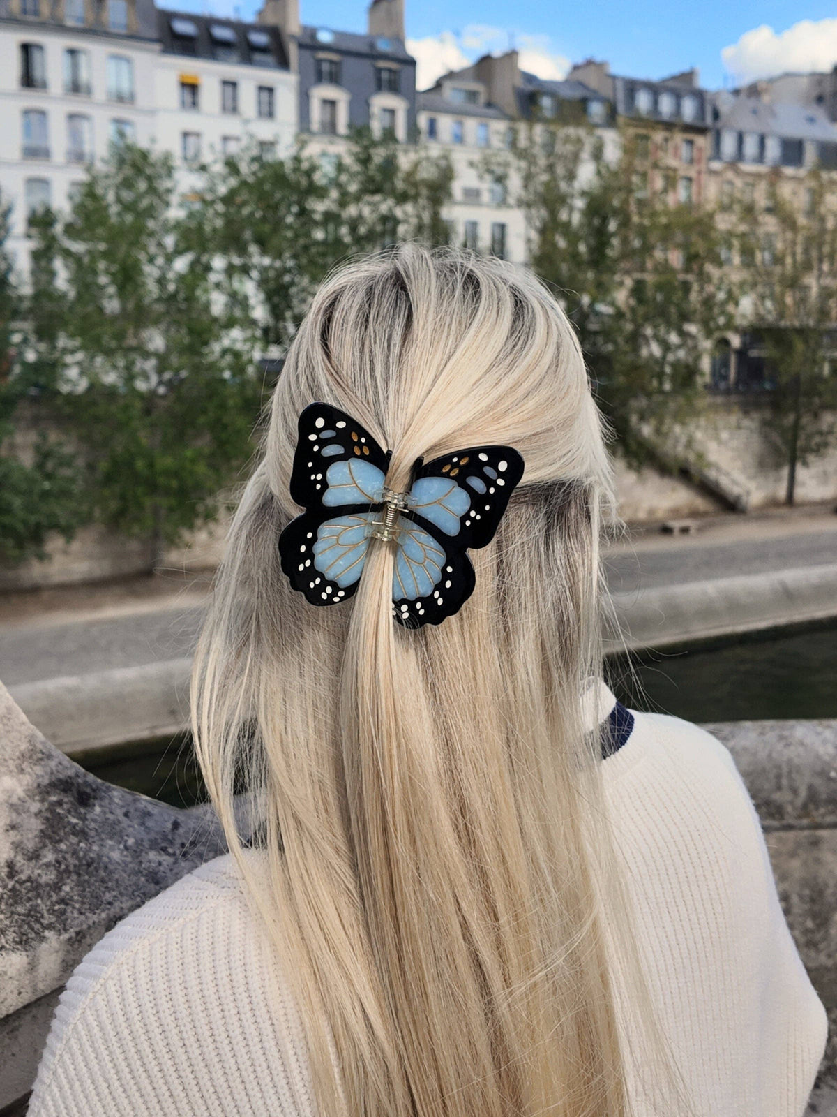 Blue butterfly clip in long blonde hair by the Seine