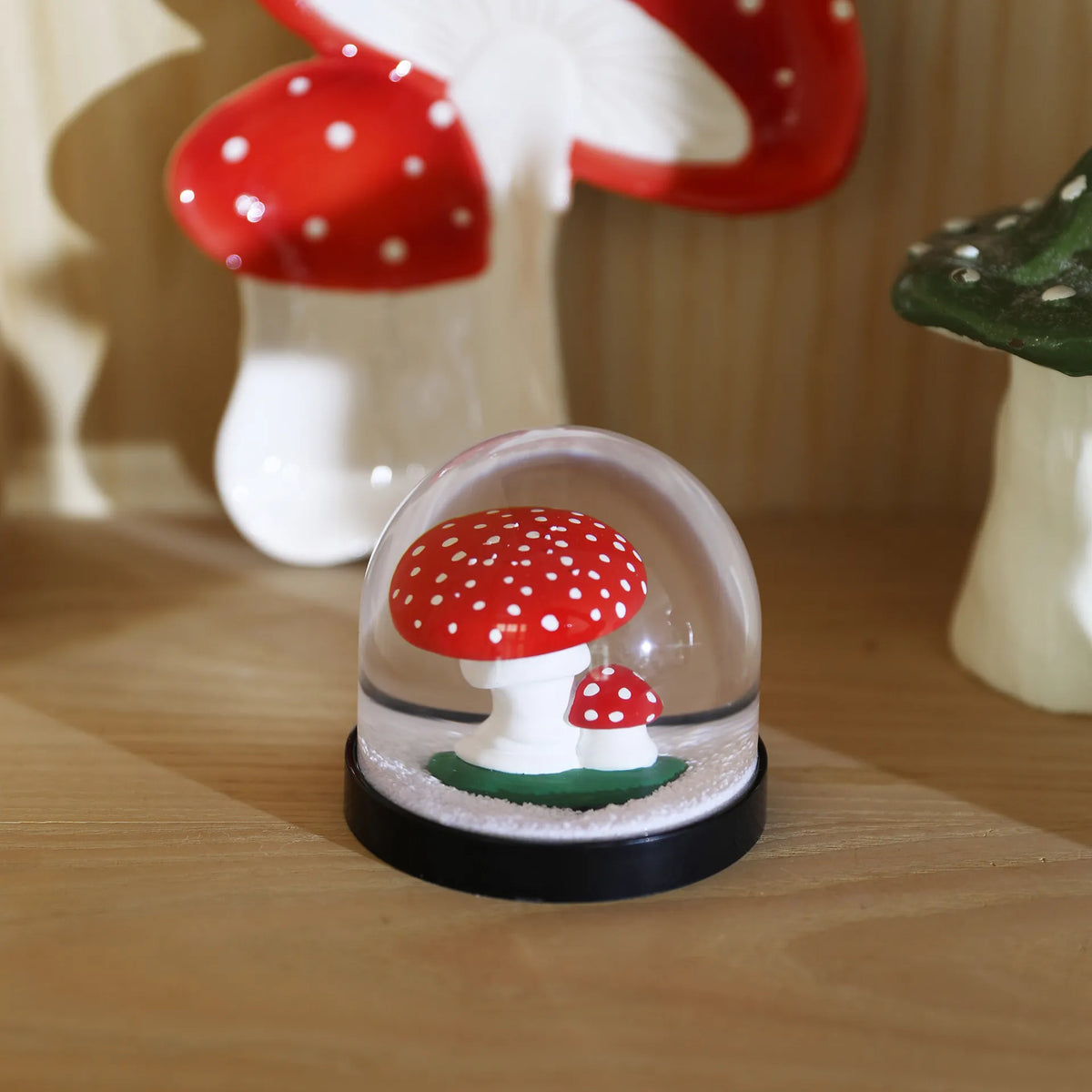 Mushroom snow globe beside larger toadstool ornaments