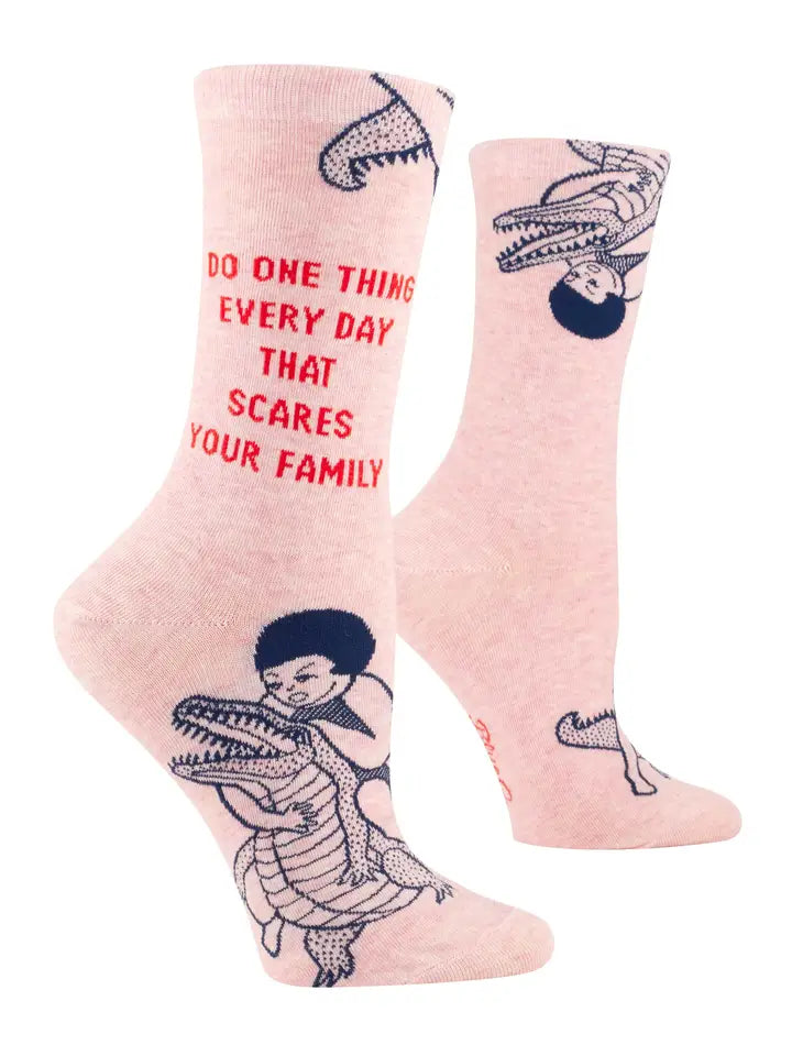 Blue Q pink socks reading 'Do one thing every day that scares your family', with a figure riding a crocodile