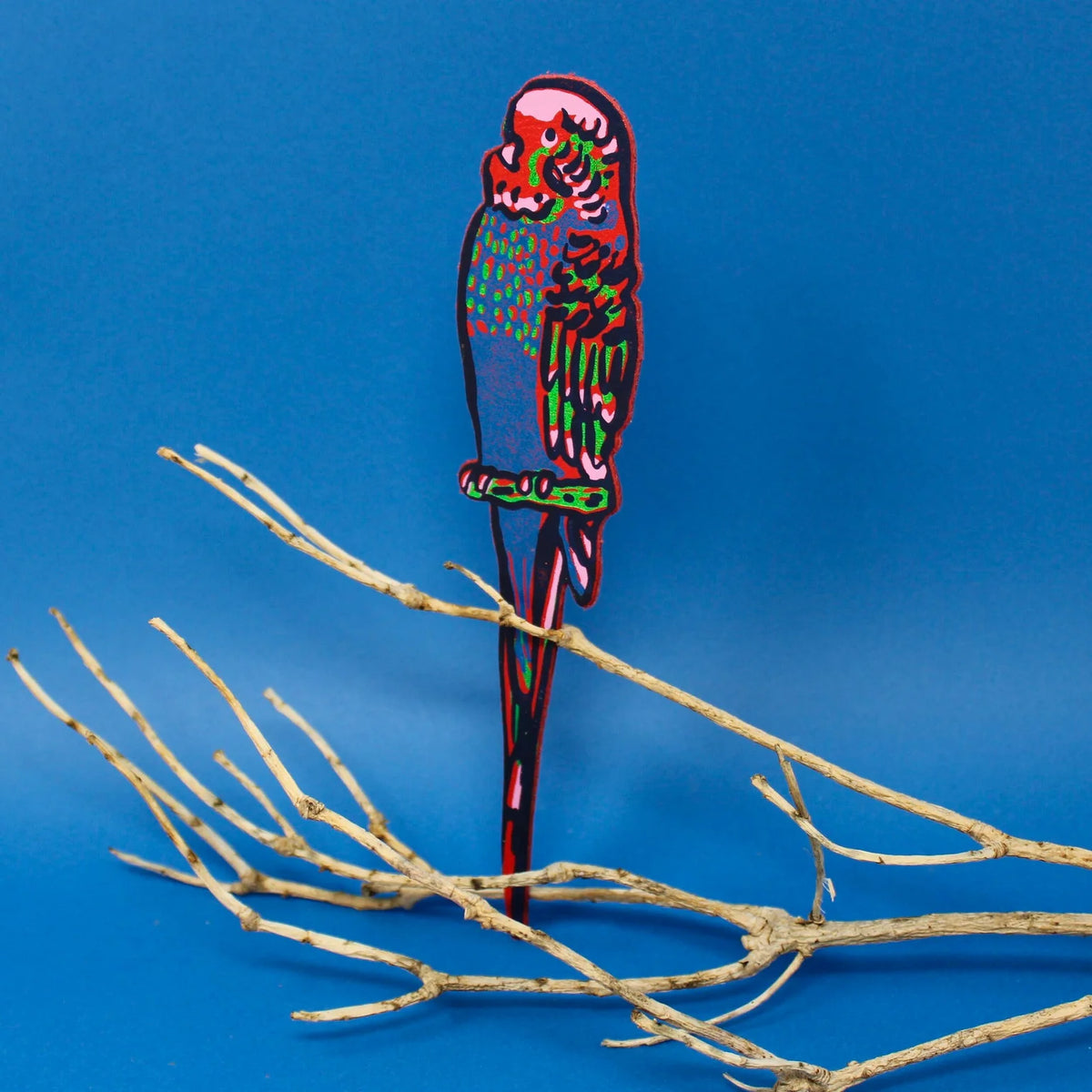 Red and green leather budgie bookmark perched on a branch
