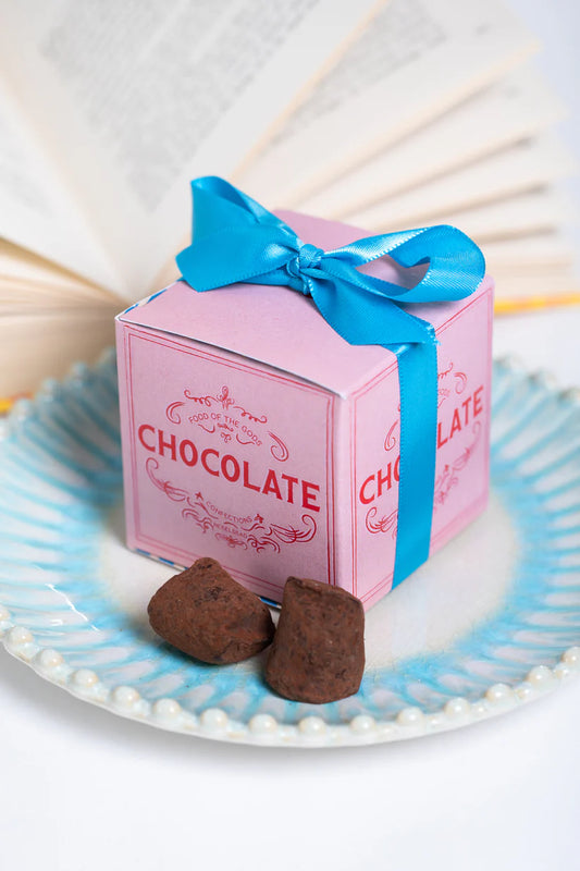 Food of the Gods chocolate and pistachio box with a blue ribbon beside truffles