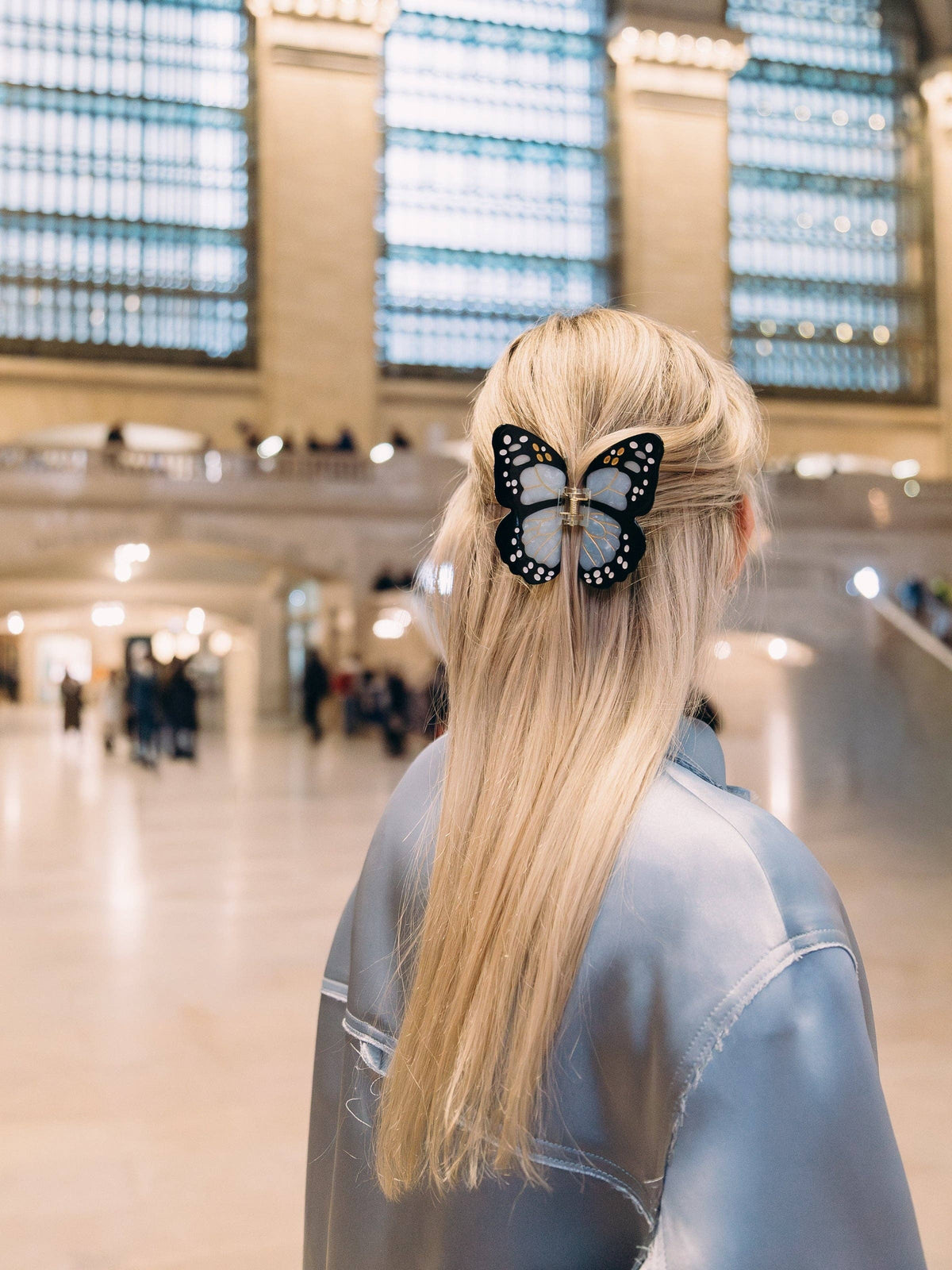 Blue butterfly clip in long blonde hair in a grand station hall
