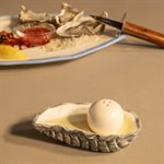 Oyster salt and pepper set on a table beside a plate of oysters