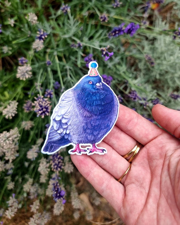 Hand holding a pigeon sticker in a party hat