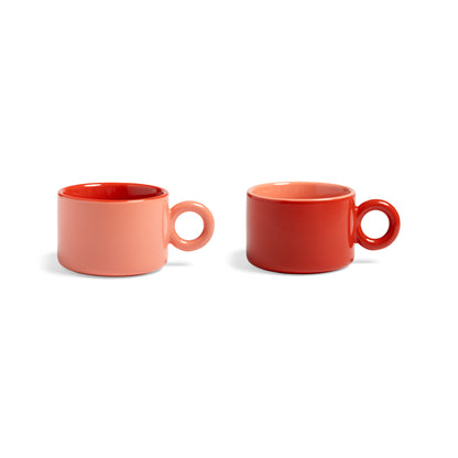 Two small ceramic mugs with round handles, one coral pink and one red