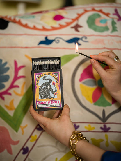 Hands lighting a match from the Magic Monkey box