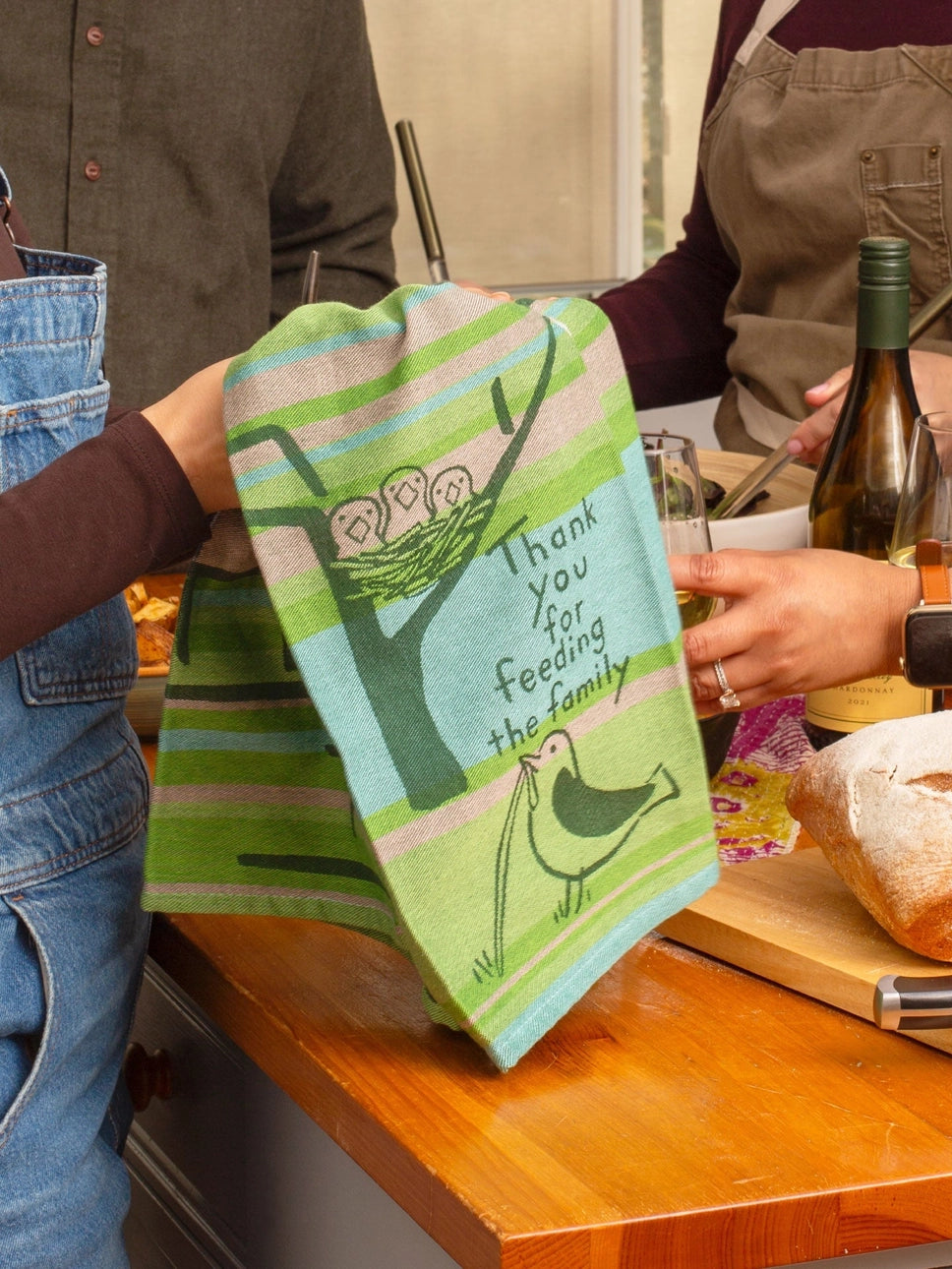 Person holding the Feeding the Family tea towel in a kitchen
