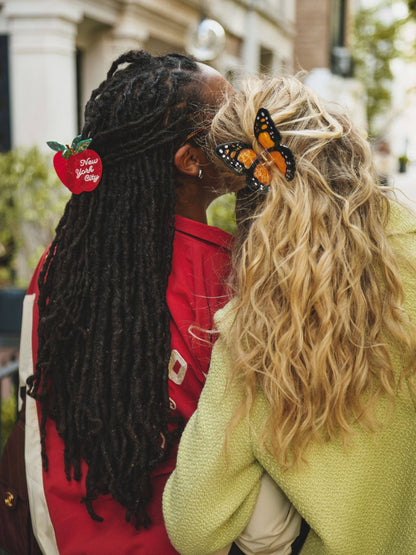 Two friends wearing butterfly and apple claw clips