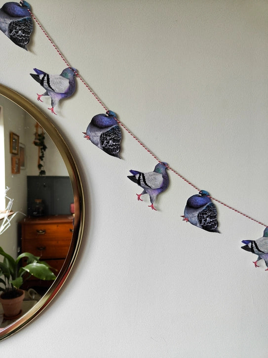 Beth Goodwin pigeon garland hanging on a wall beside a round mirror