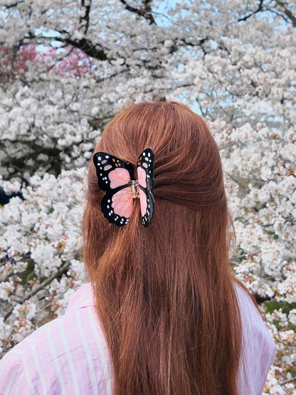 Pink butterfly clip in long auburn hair under cherry blossom