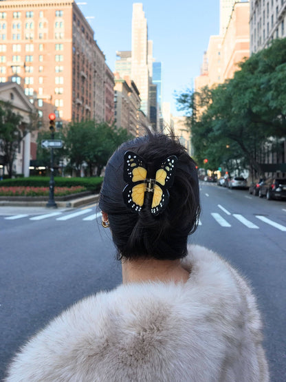Close-up of the orange monarch clip in dark hair on a city street