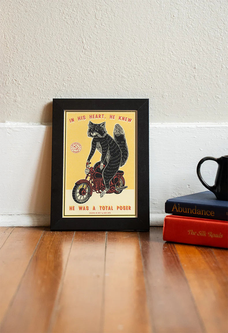 Total Poser print in a black frame on a wooden floor