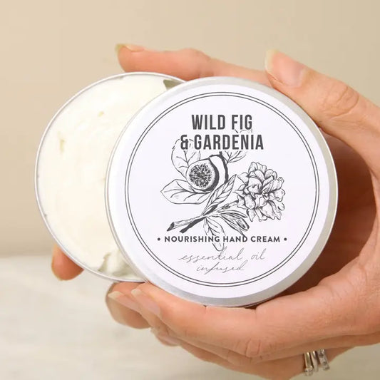 Hands holding an open tin of Norfolk Natural Living Wild Fig & Gardenia hand cream