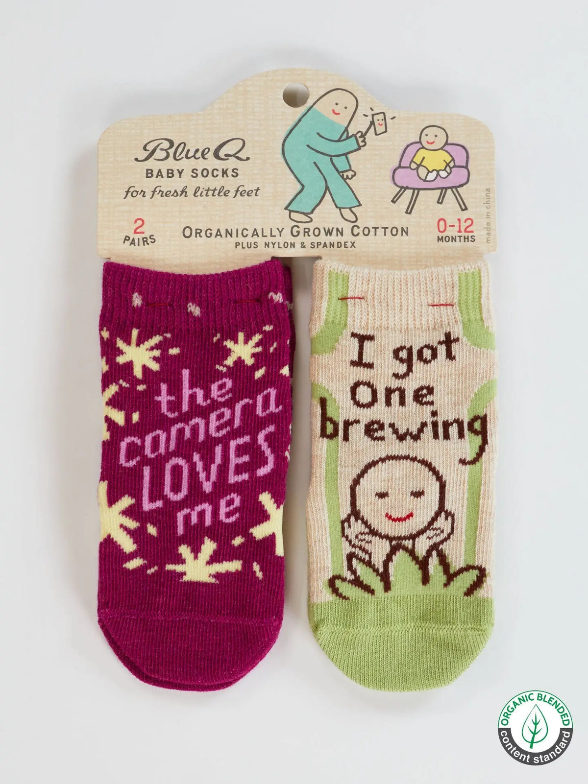 Blue Q baby socks, two pairs: 'The camera loves me' in magenta and 'I got one brewing' in cream and green