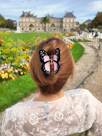 Close-up of the lilac butterfly clip in a bun in front of a palace garden