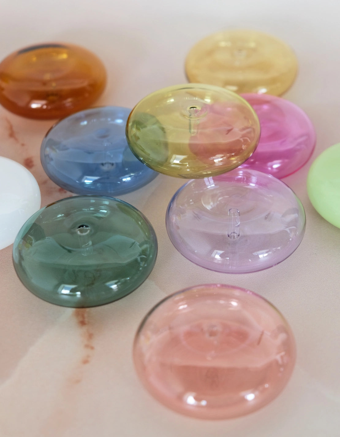 Botanica glass incense holders in a range of colours scattered on marble