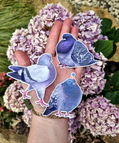 Beth Goodwin pigeon vinyl stickers held in a hand among hydrangeas