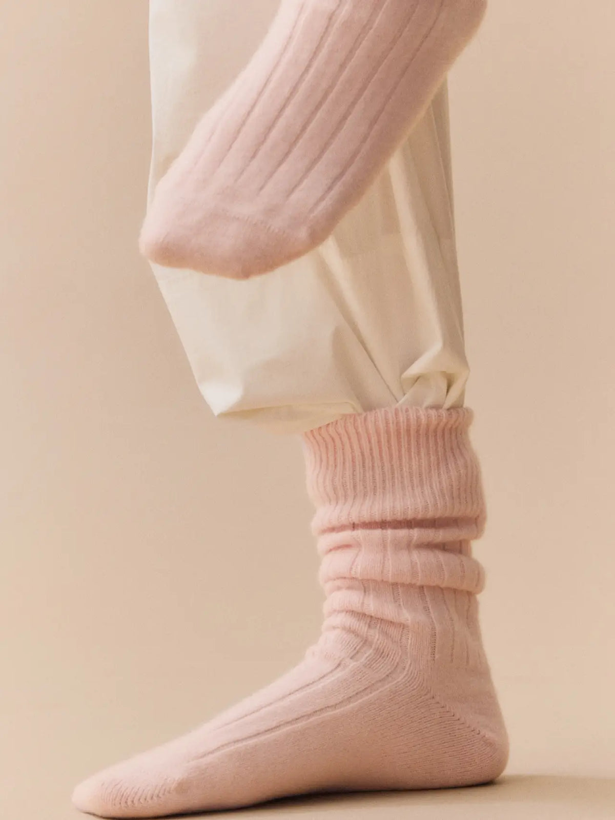 Person wearing frosting pink bed socks with cream trousers