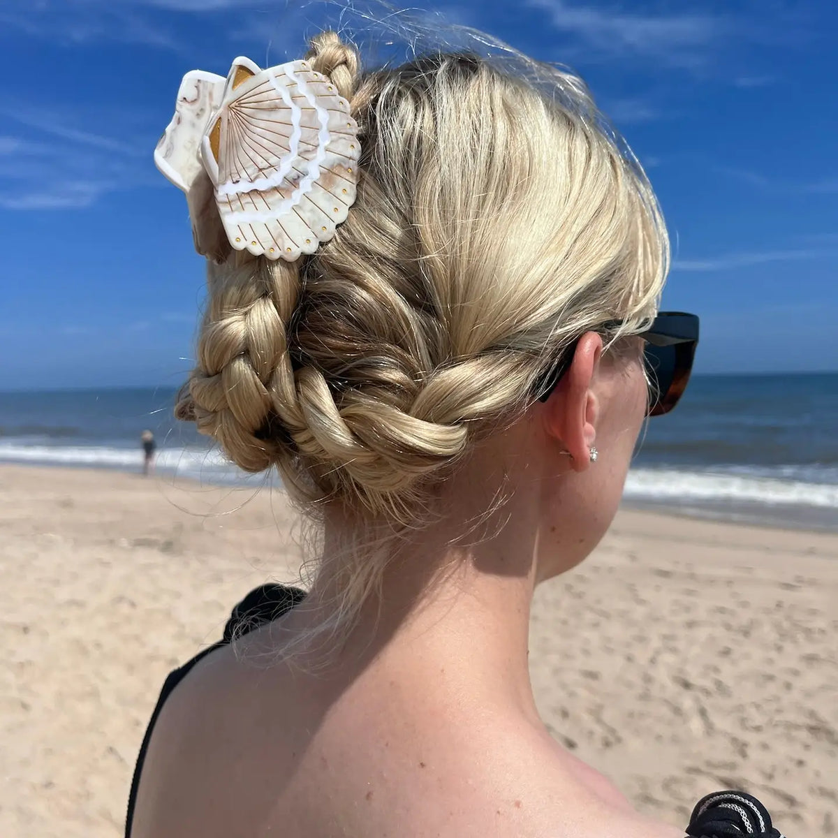 Woman on a beach with the seashell clip in braided blonde hair