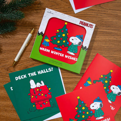 Snoopy Christmas cards and their box on a wooden table with a pen