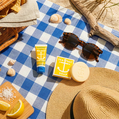 Sea salt soap and hand cream on a gingham picnic blanket with sunglasses and lemons
