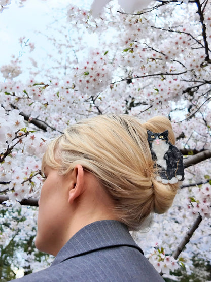Woman wearing the tuxedo cat clip under cherry blossom