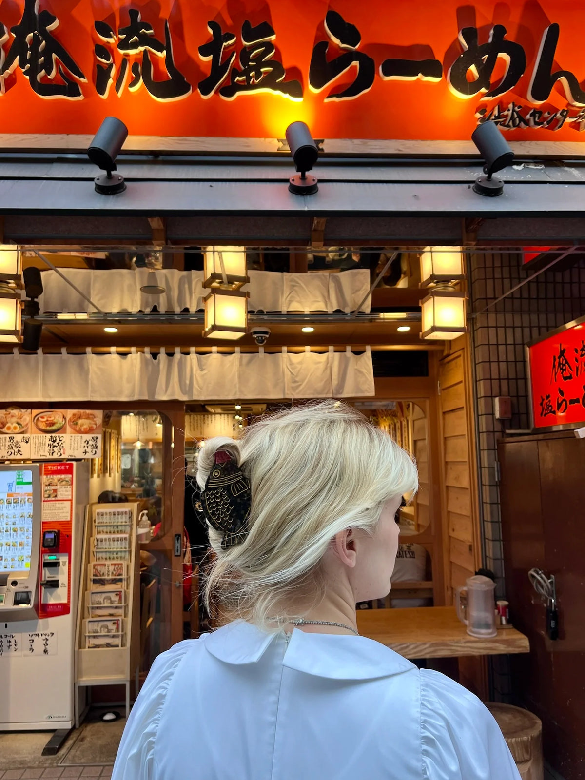 Woman wearing the soy sauce clip outside a ramen shop