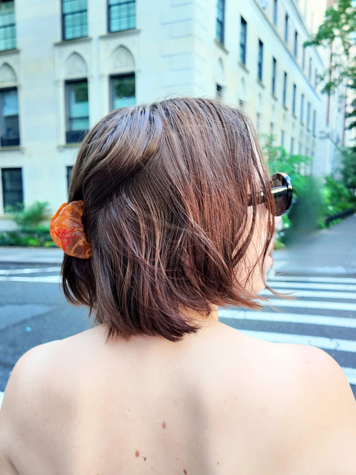Mini croissant claw clip in a brown bob on a city street