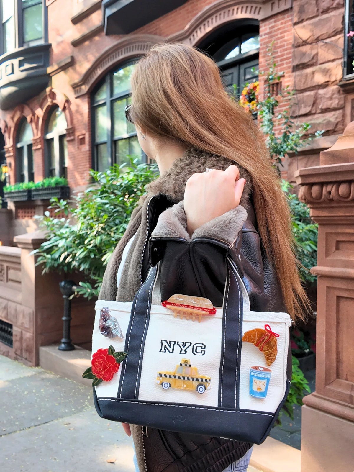 Brooches including the horseshoe on a tote bag, worn on a city street