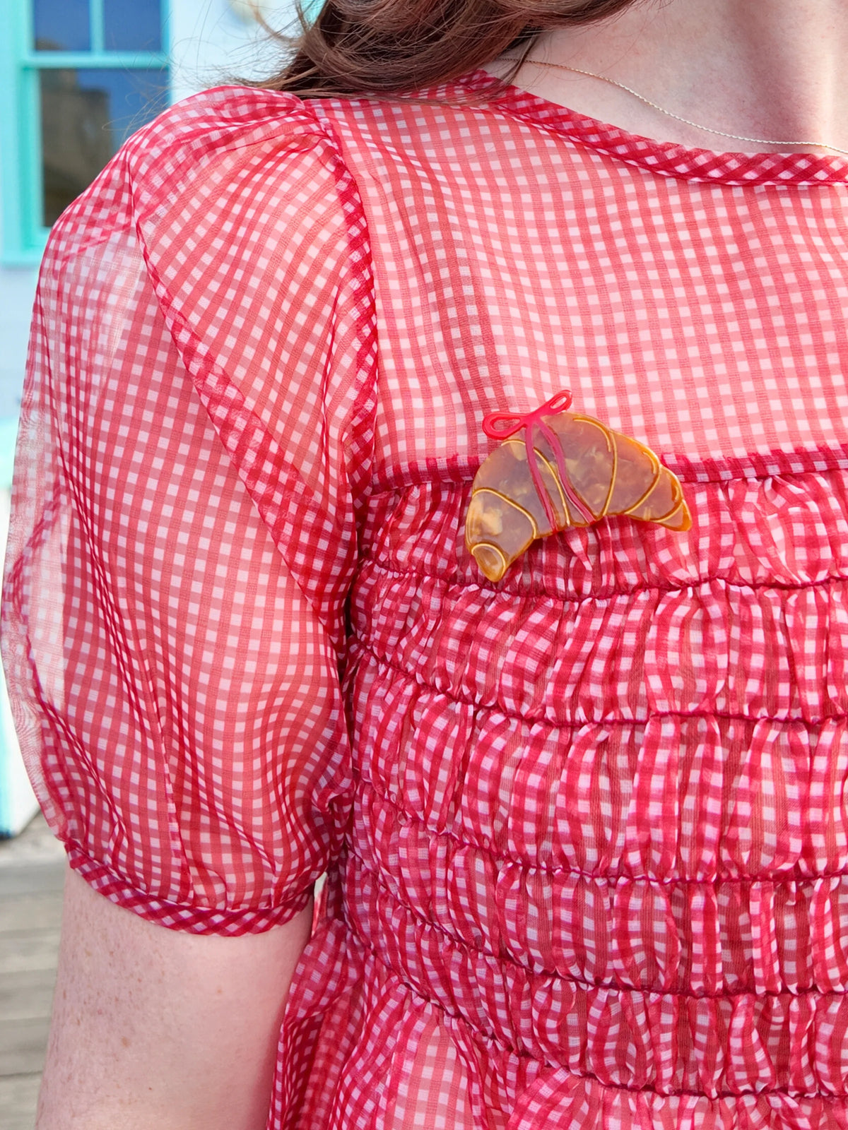 Croissant brooch on a red gingham blouse