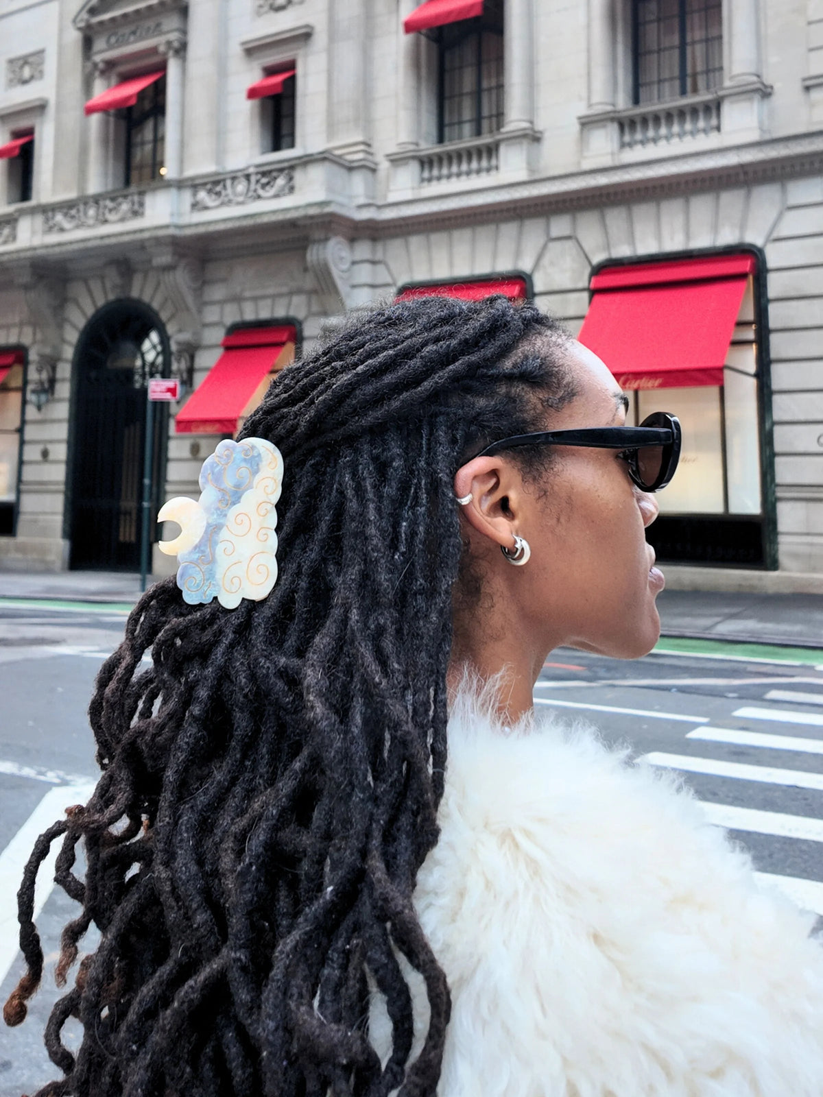 Woman wearing the moon claw clip in long locs on a city street
